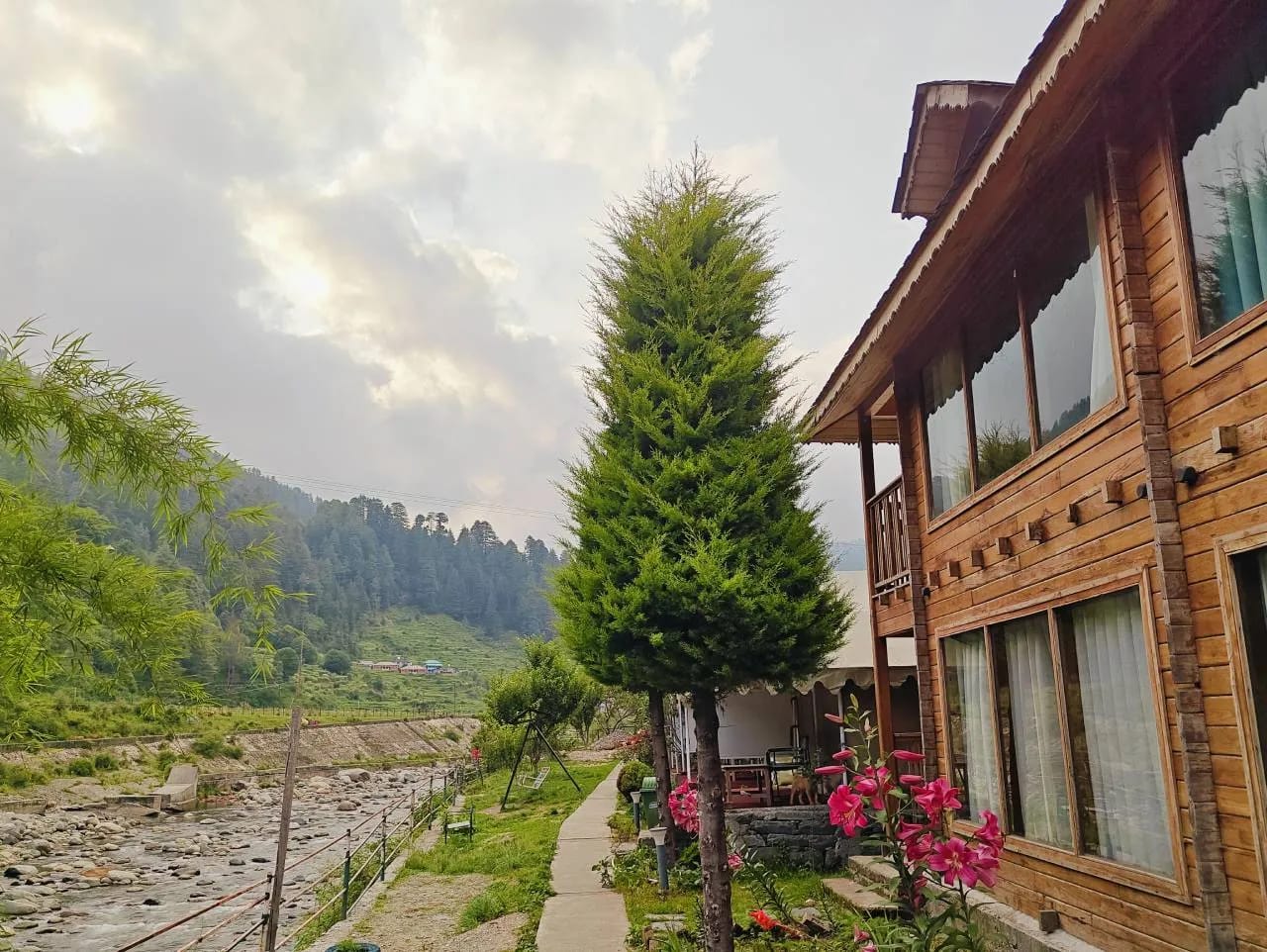 Wooden cottages beside the Uhl river at The Heimat Resort, Barot Valley